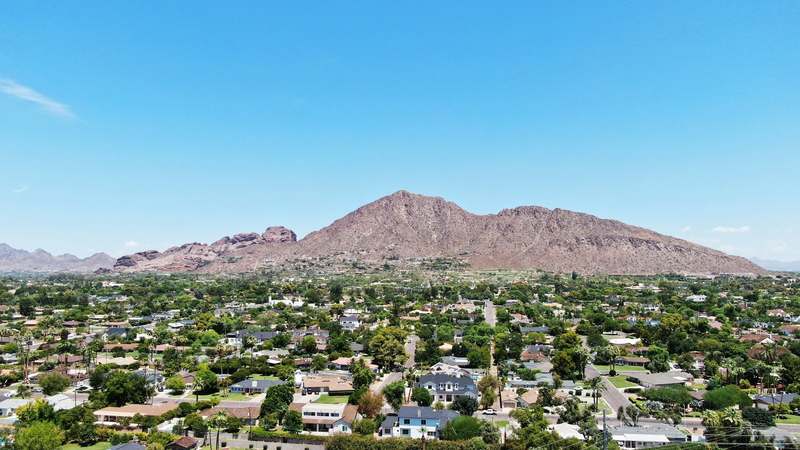 Camelback Mountain rising above tree-lined Phoenix neighborhoods under a clear sky
