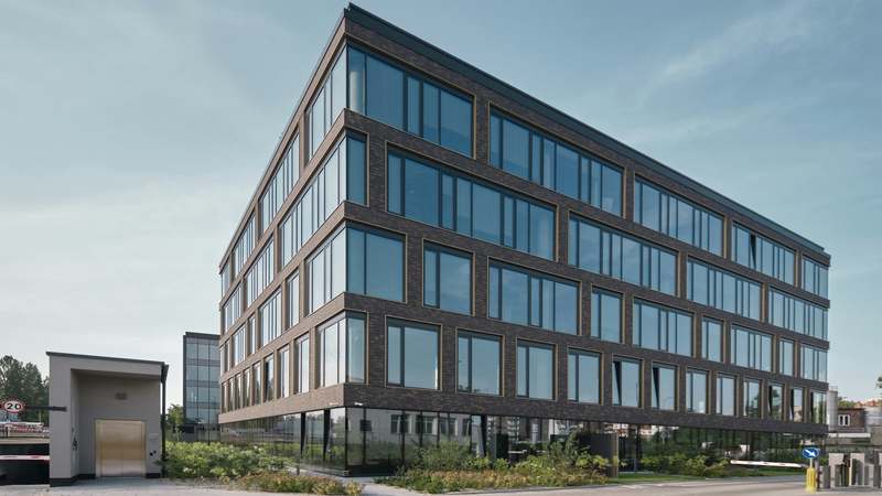Four-story office building with a dark grid facade and glass windows