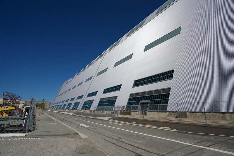 Large flex industrial building with a silver metal facade under a deep blue sky