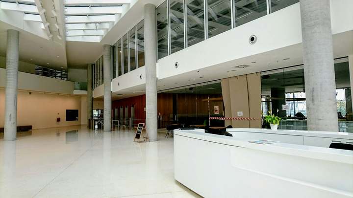 Bright two-level office lobby with a white reception desk and columns