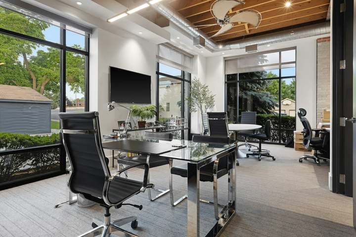 Furnished office suite with desks, mesh task chairs, and large windows