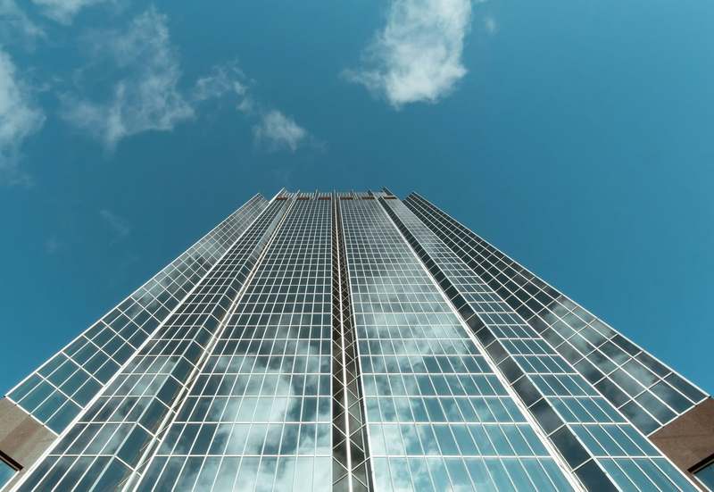 Looking up the glass facade of an office tower against a blue sky