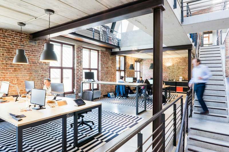 Person walking down the stairs of a loft-style office with brick walls
